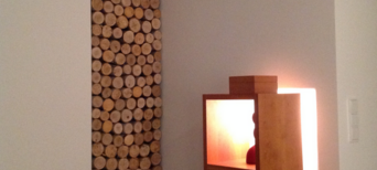 Gestapelte runde Holzscheite als dekorative Wandgestaltung neben beleuchtetem Holzschrank in modernem Wohnraum.