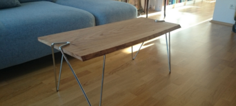 Minimalistischer Couchtisch mit Massivholzplatte und filigranen Metallbeinen im Wohnzimmer mit Holzboden.