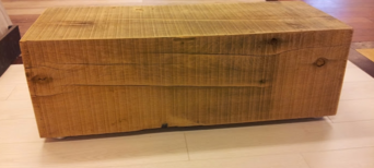 Schlichter Möbelblock aus grob bearbeitetem Massivholz in einer Ausstellung mit verschiedenen Holzböden.